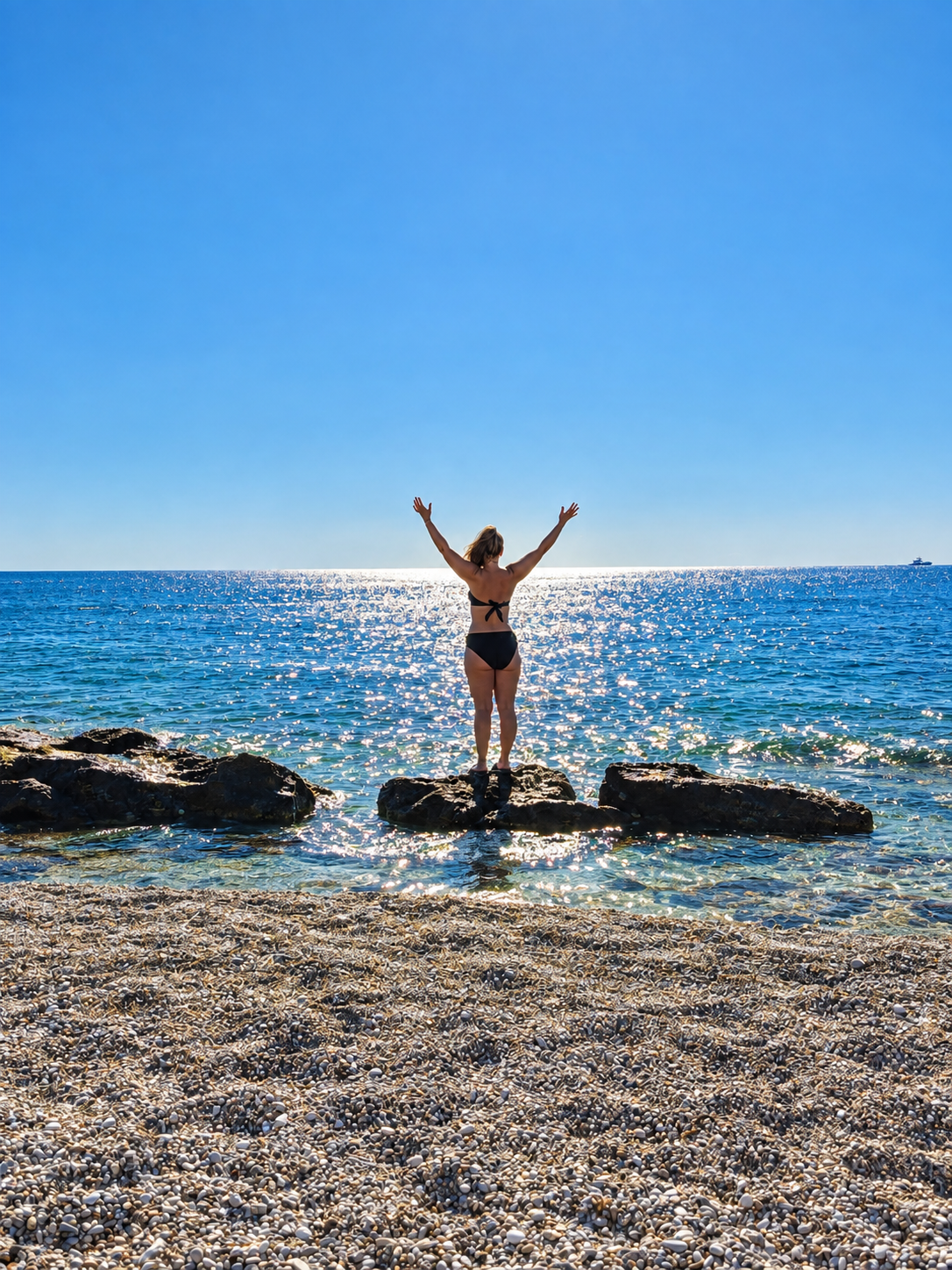 Sandra med armarna upp mot himlen vid havet